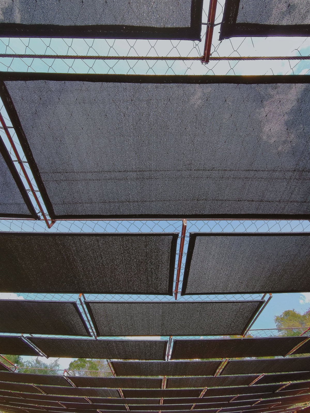 Black overhead shade cloth panels in an outdoor installation.